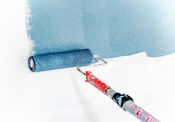 A paint roller is painting a white wall blue.